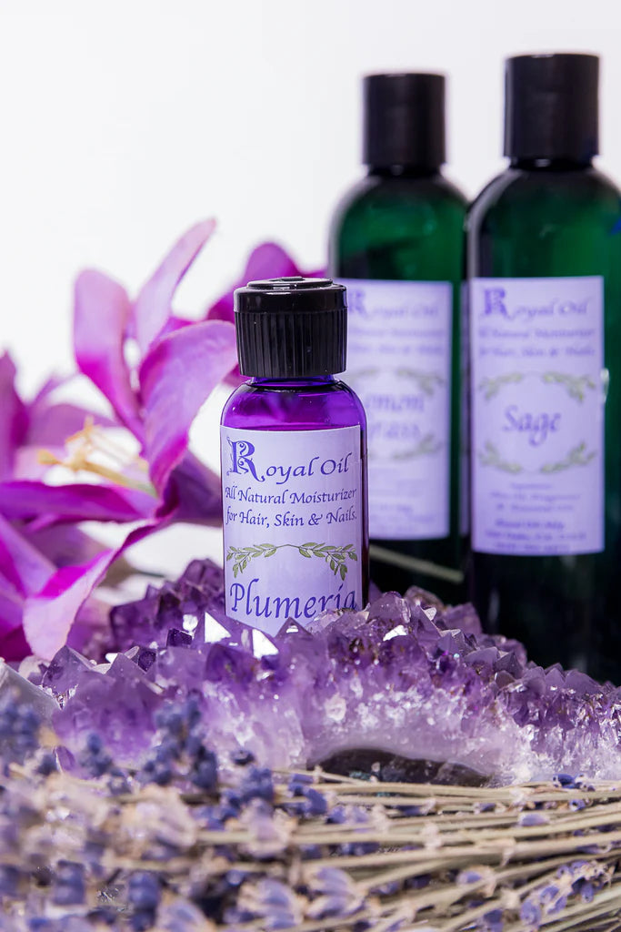 Three bottles of Royal Oil with floral and crystal decorations on a white background